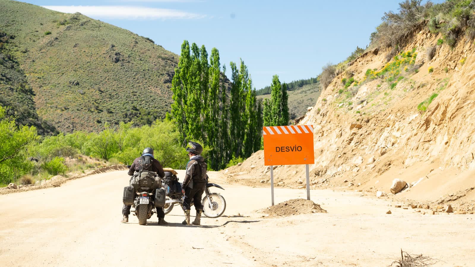 Dos pilotos detenidos junto a un cartel de desvío durante una exploración de ruta.