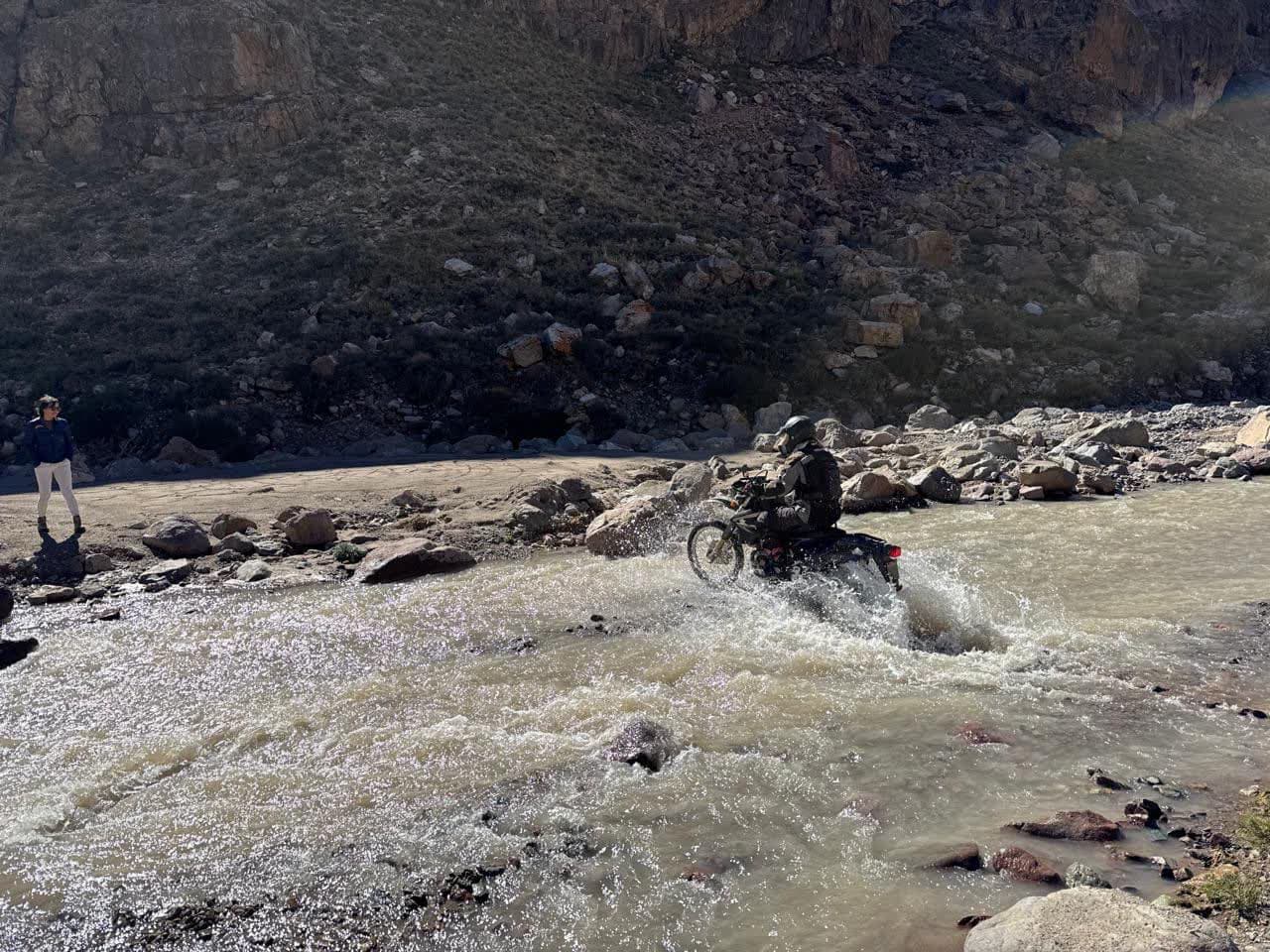 Piloto cruzando agua sobre una moto durante el armado de Cruces del Sur.