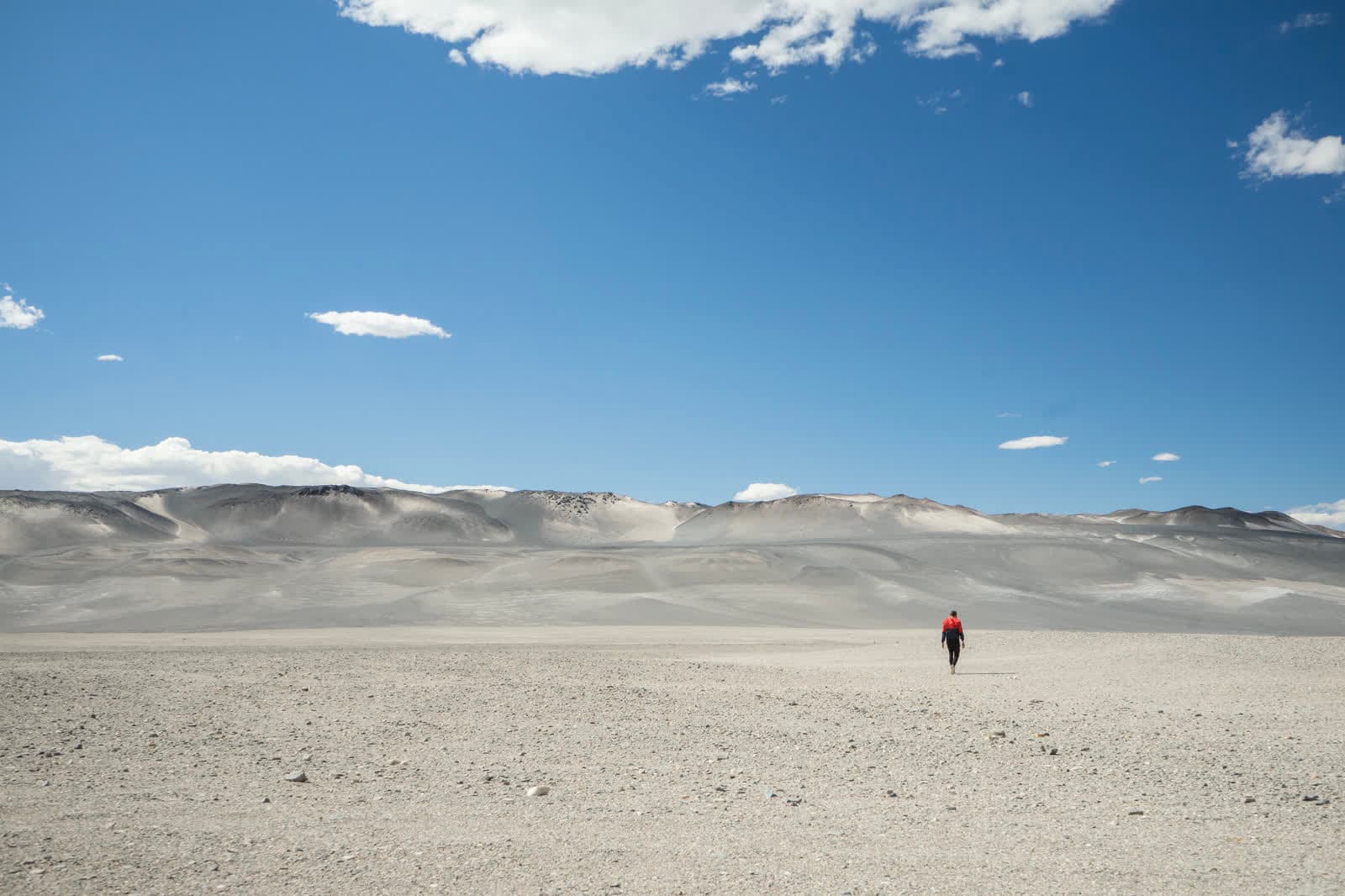 Campo de altura en Catamarca con una persona caminando hacia la montaña.