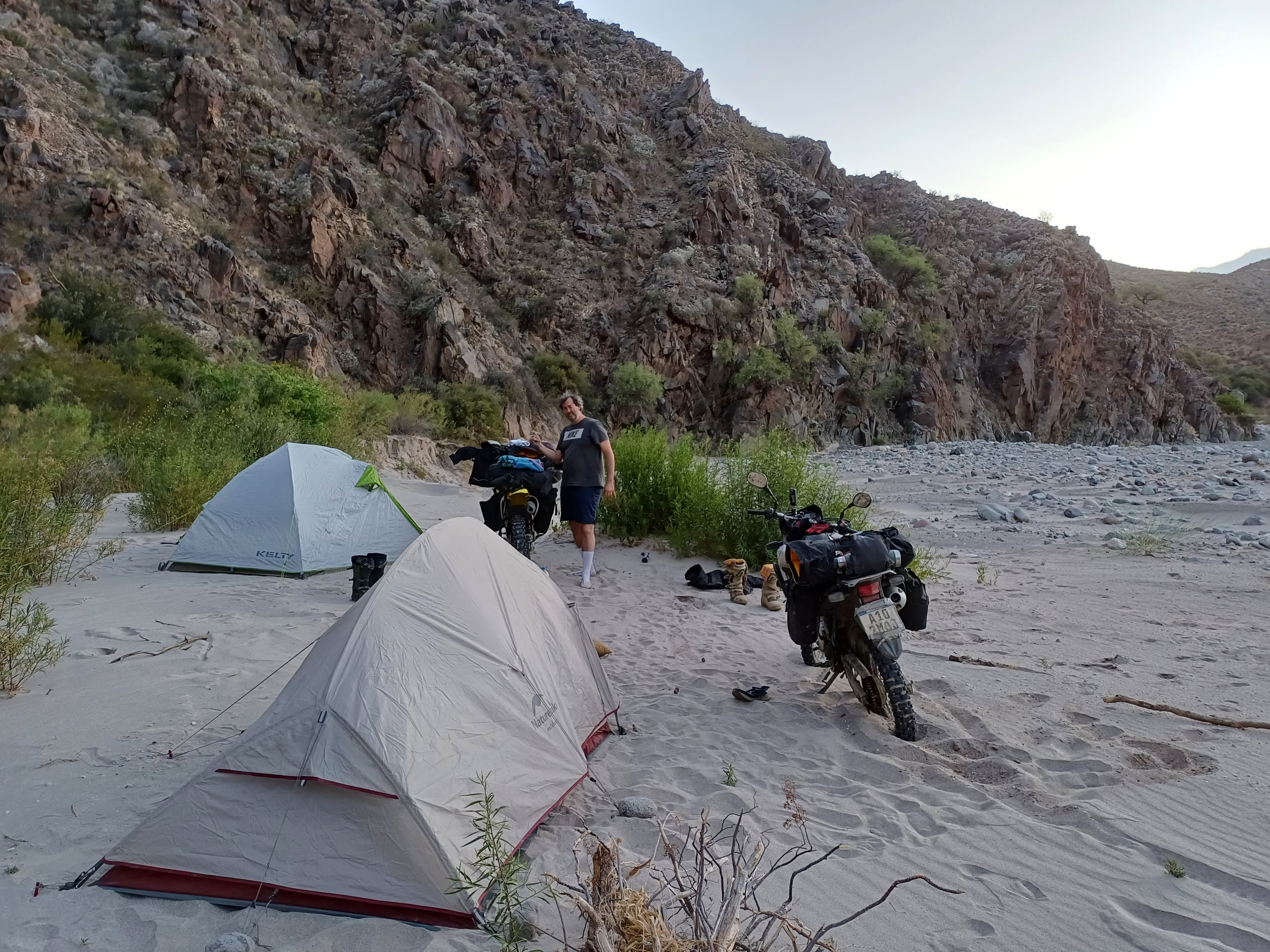 Campamento de motos en un arenal entre paredes rocosas de Catamarca.