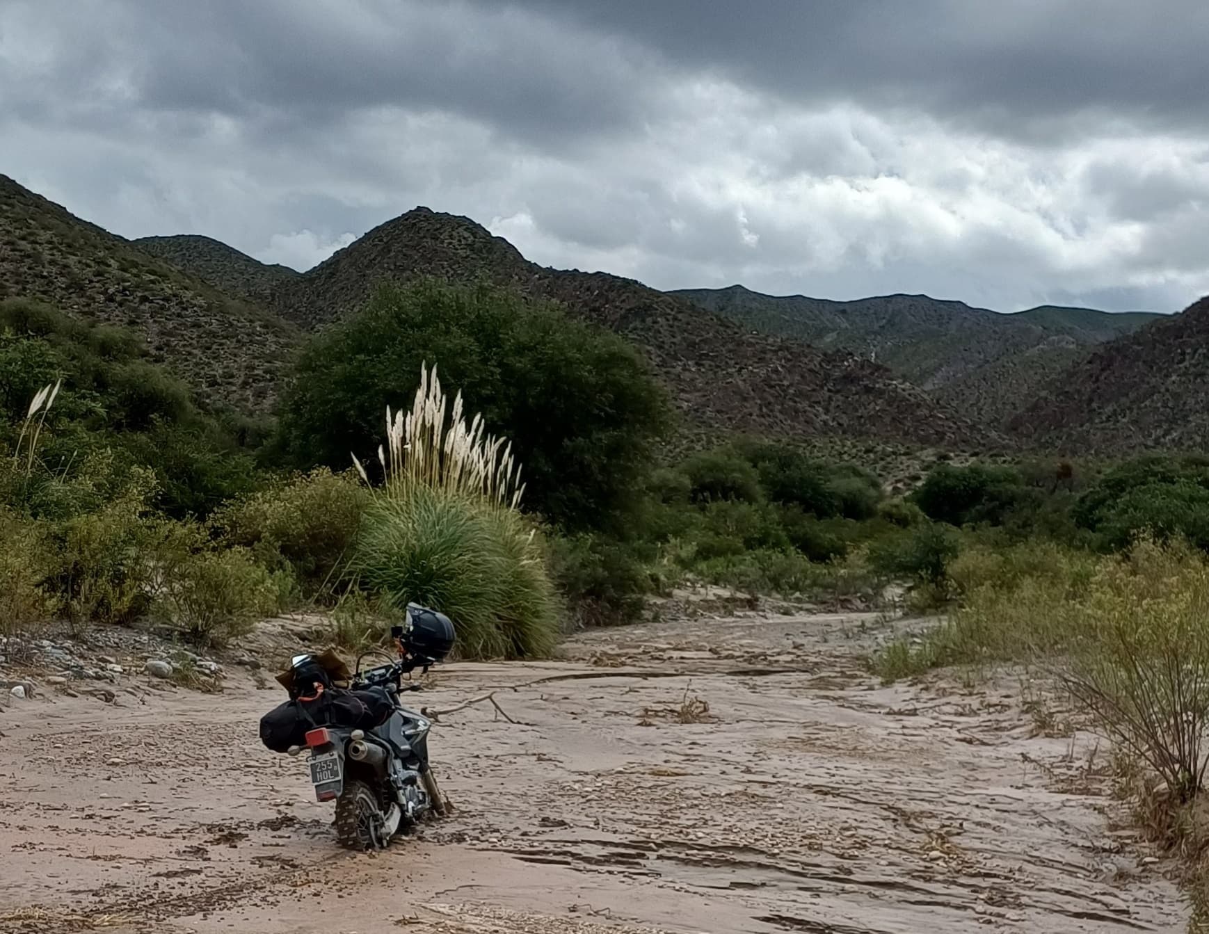Moto detenida en un camino arenoso bajo nubes de tormenta en Catamarca.